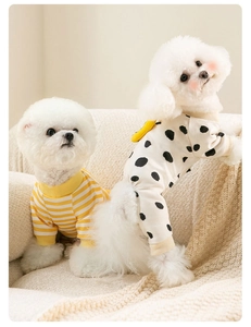 Detail view of yellow striped and polka dot cotton pet clothes on white puppies