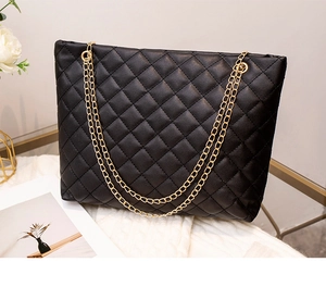 Gros plan d'un sac à bandoulière matelassé noir avec chaînes dorées sur texture blanche