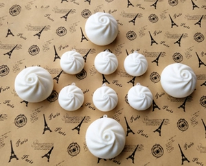 Set of ten white steamed bun charms with metal rings on a vintage paper background