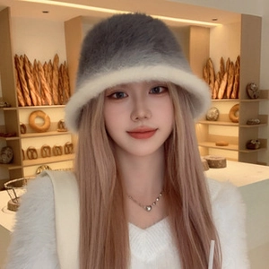 Primer plano de un gorro bucket de felpa suave en degradado gris y beige en modelo