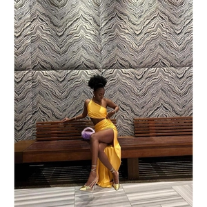 Détail d'un ensemble deux pièces jaune en soie avec haut asymétrique et jupe longue fendue
