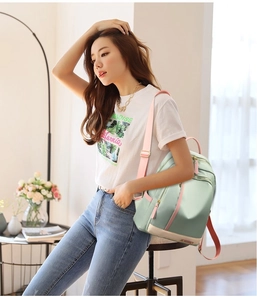 Light green nylon backpack with pink straps shown on a model in a bright home setting
