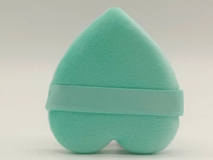 Detail of a heart-shaped teal velvet powder puff with matching finger ribbon strap