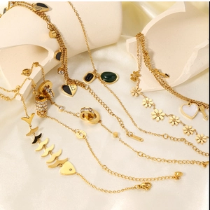 Detailed close-up of gold chain bracelets with heart pendant and emerald green zircon
