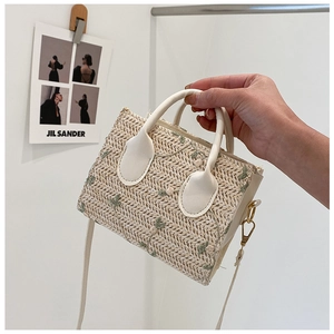Detail of floral embroidery on cream straw tote bag with vegan leather handles