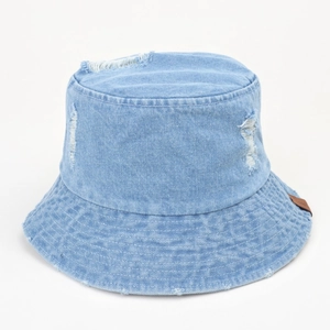 Détail d'un chapeau bob en jean bleu clair avec trous usés et patch en cuir marron