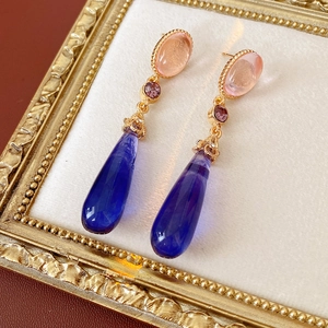 Détail de boucles d'oreilles vintage de style palais avec résine rose et bleue et cadre doré