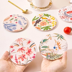 Close-up of ceramic coasters featuring tropical toucan and floral botanical patterns