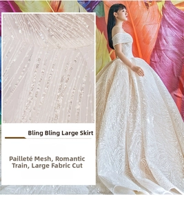 Detail of starry sequin mesh fabric on an off-shoulder bridal gown with luxury long train