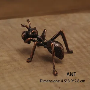 Dettaglio macro di una scultura di formica in ottone vintage su fondo di legno