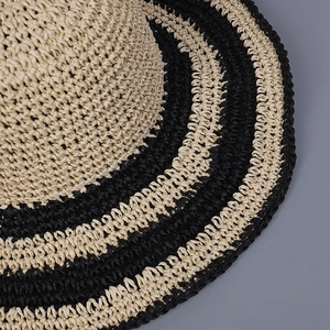Close-up of hand-woven beige and black striped texture on large brim straw sun hat