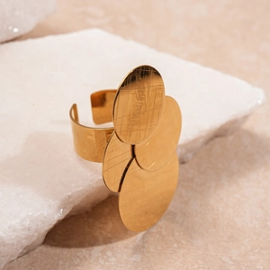 Detail of gold metal ring featuring three overlapping discs with a brushed matte texture