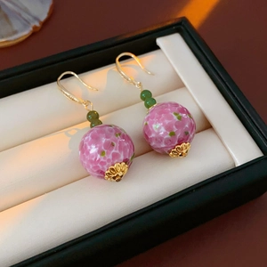 Makroansicht von Glasperlen-Ohrringen mit Blumenmuster und Goldhaken in einer Schmuckbox
