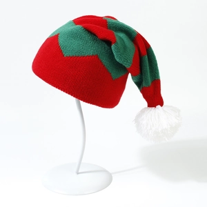 Macro view of knit texture and white pompom on a red and green Christmas elf hat