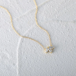 Detail of gold necklace featuring marquise cut stones on a textured stone background