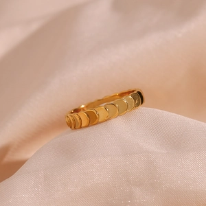 Macro detail of 18K gold plated ring with fish scale texture on pink silk fabric