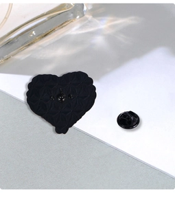 Detail of black heart enamel pin back featuring textured metal and butterfly clasp