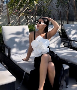 Close-up of a stylish black swimsuit with a large 3D white floral camellia decoration