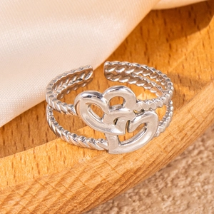 Macro detail of silver hollow heart layered steel ring on elegant silk and wood stand