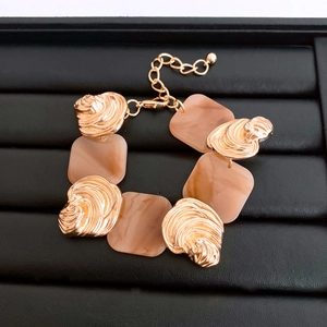 Macro shot of French luxury gold shell charms and beige marble resin square bracelet links