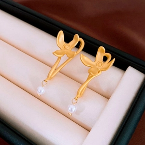 Detailed close-up of matte gold flower earrings with elegant white pearl drops in box