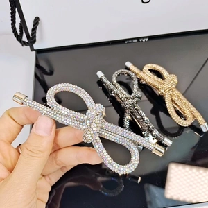 Dettaglio di eleganti fermagli a fiocco con strass in argento, oro e canna di fucile