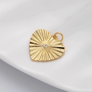 Macro view of a gold-plated heart pendant with sunburst texture and central zircon crystal