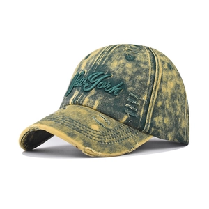 Detail of vintage washed green denim baseball cap with distressed holes and New York embroidery