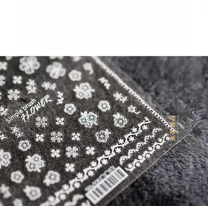 Detail of white floral nail decals with minimalist lace patterns on dark background