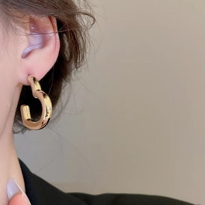 Gros plan sur une boucle d'oreille dorée irrégulière avec une finition polie