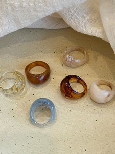 Detail view of assorted resin rings with amber and marble patterns on a ceramic tray