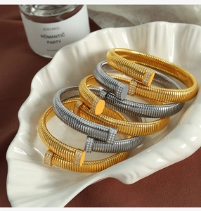 Close-up of gold and silver nail bracelets with spiral texture and sparkling crystals