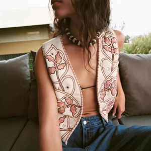 Vintage embroidered vest with floral patterns and mirror details on beige fabric