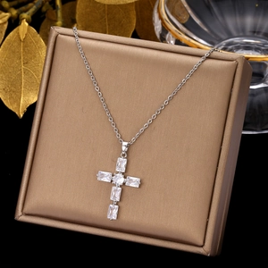 Detalle de collar de cruz plateado con circonitas sobre un joyero marrón de calidad