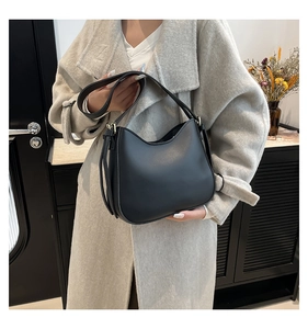 Classic black leather handbag shown by model with minimalist interior background