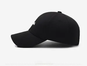 Detail of white cursive embroidery on a black structured cotton baseball cap side