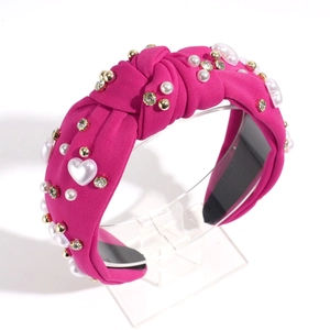 Detail of fuchsia knotted headband featuring heart pearls and sparkling rhinestones