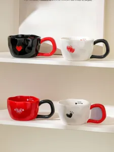 Detail of four ceramic heart mugs in red black and white with Love pattern design