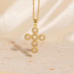 Elegant gold cross necklace with sparkling zircon pendants on a luxury fabric background
