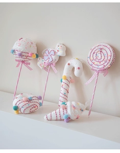 Close-up of pink knitted Christmas candy cane and lollipop ornaments with colorful pom-poms