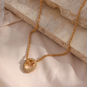 Close-up of golden twist chain necklace with double-layer zircon circle pendant on silk
