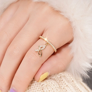 Close-up of golden butterfly pendant ring with shimmering zircon inlays on woman's hand