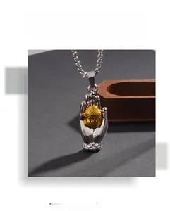 Macro detail of bicolored Buddha hand pendant with gold head and silver polished finish