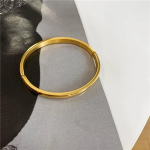 Close-up of minimalist 18K gold plated titanium steel bangle on a magazine background
