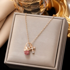 Makroaufnahme der Goldhalskette mit rosa Strasskugel und Kreuzanhänger auf Schmuckdose