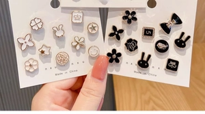 Detailed close-up of a diverse pearl earring set featuring clover and animal motifs