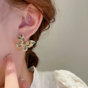 Close-up of golden butterfly earring with colorful crystals on a model's ear
