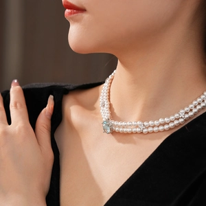 Détail d'un collier de perles à double rang avec un grand pendentif en pierre bleue sur modèle