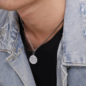 Close-up of a silver dual-chain necklace featuring a round engraved pendant on a model