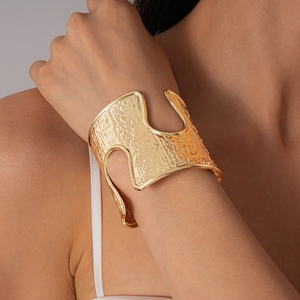 Detail of gold hollow cuff bracelet featuring textured hammered surface on model